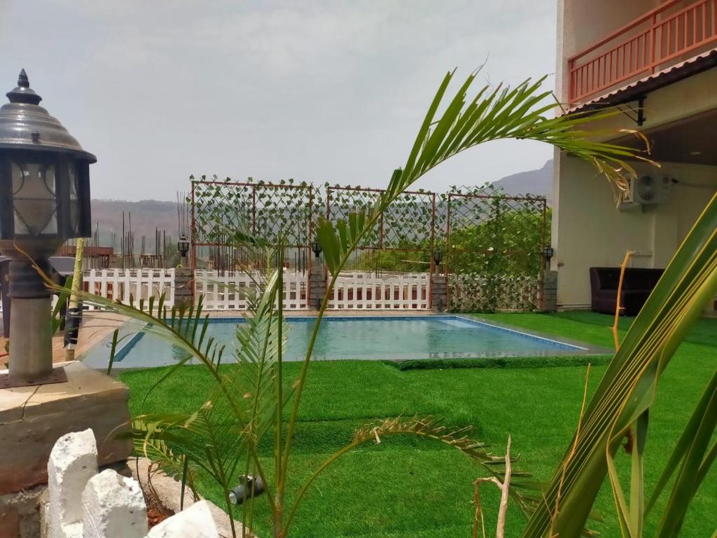 een achtertuin met een zwembad en groen gras bij THE DECK in Karjat