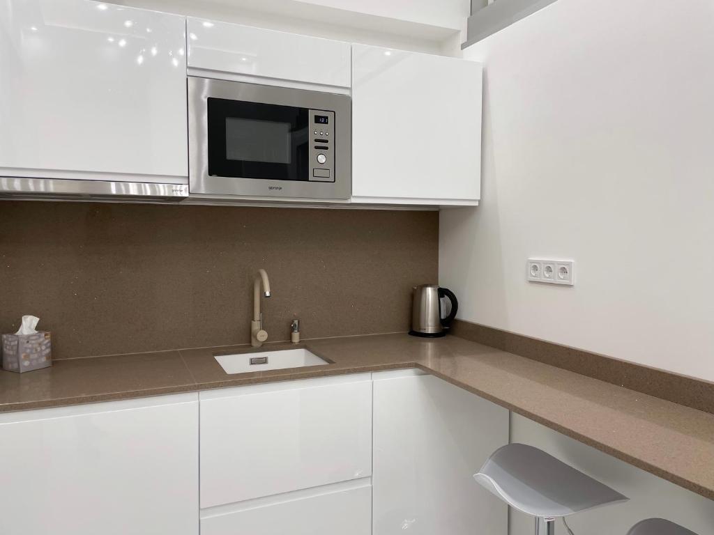 een keuken met witte kasten en een magnetron bij St Stephen Luxury Apartment in Boedapest