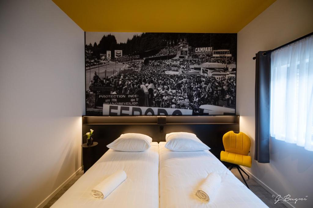 two beds in a room with a picture of a hockey game at La Reine Hôtel - Restaurant , City Centre in Spa