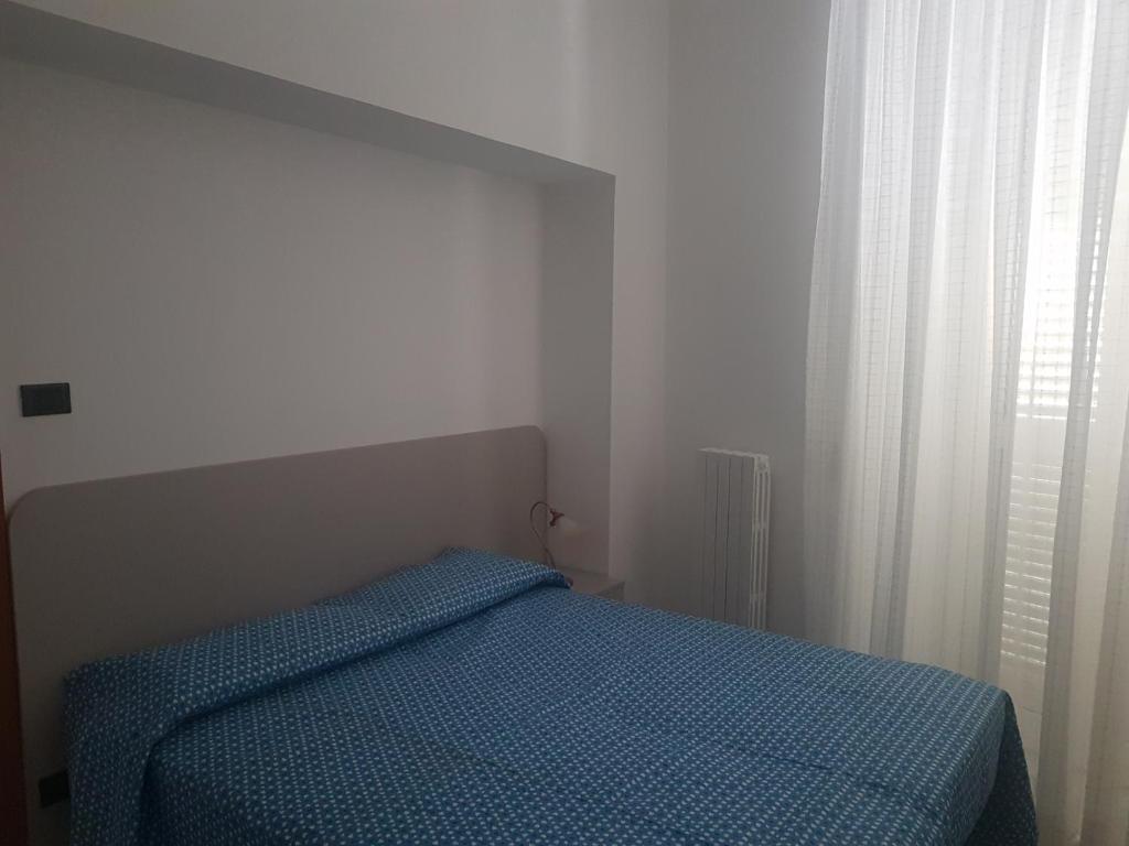 a bedroom with a bed with a blue comforter and a window at I ciclamini in Monopoli