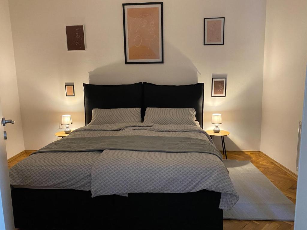 a bedroom with a large black bed with two lamps at Várker 9 Apartman in Sopron