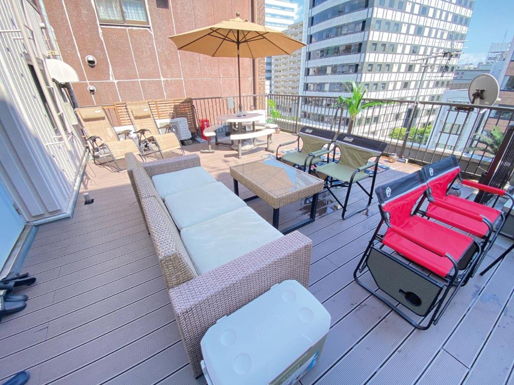 uma varanda com cadeiras e mesas e um guarda-sol em commun ryogoku - Vacation STAY 97137v em Tóquio