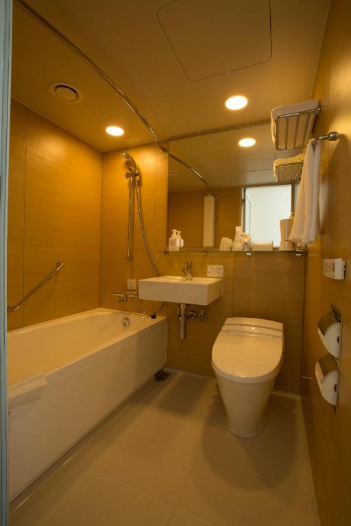 a bathroom with a tub and a toilet and a sink at JR Kyushu Hotel Blossom Shinjuku in Tokyo