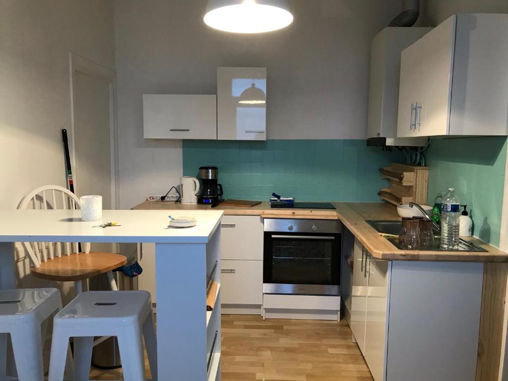 a kitchen with white cabinets and a table and chairs at La maison de Sloan in Guéret