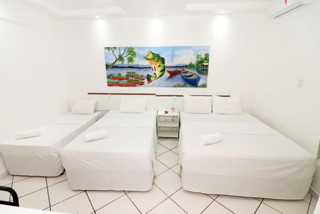 a room with three beds and a painting on the wall at Prata Hotel in Santarém