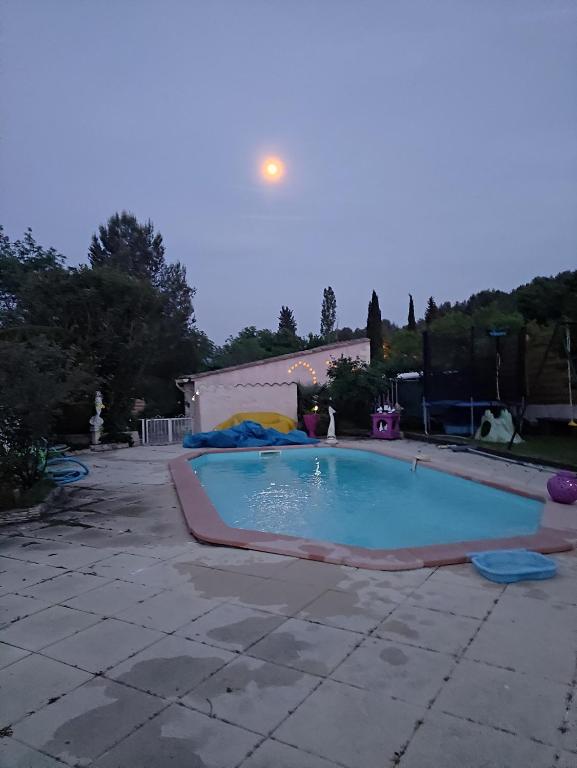 a large swimming pool in a yard with the moon in the sky at Le soleil de provence in Peypin
