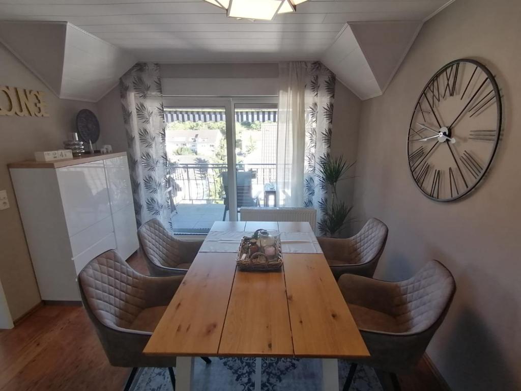 a dining room table with chairs and a clock on the wall at Romantische Ferienwohnung in Bad Breisig