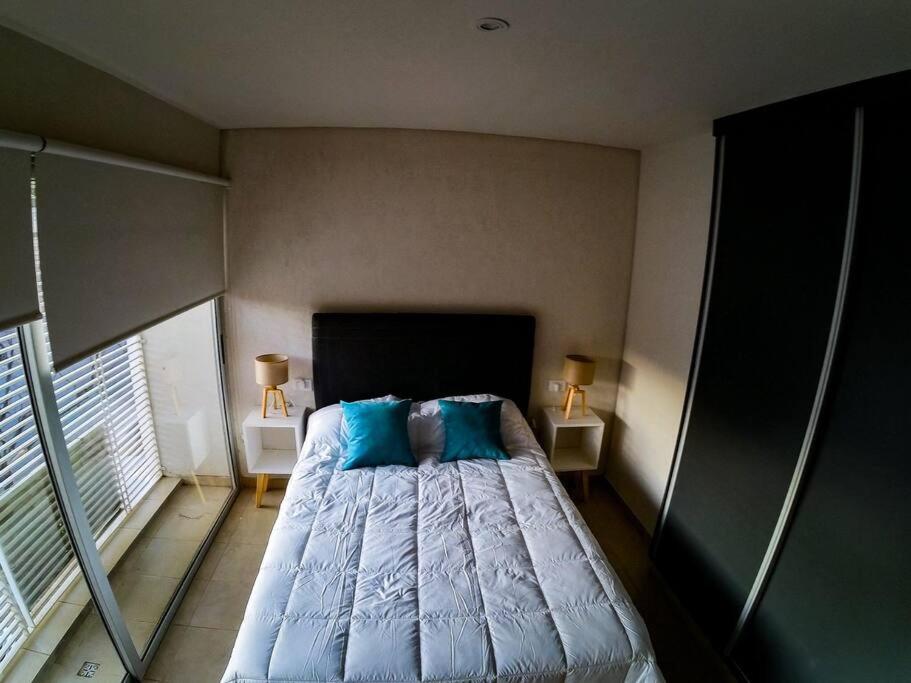 a bedroom with a bed with blue sheets and two lamps at Departamento Soberania totalmente amoblado in La Cieneguita