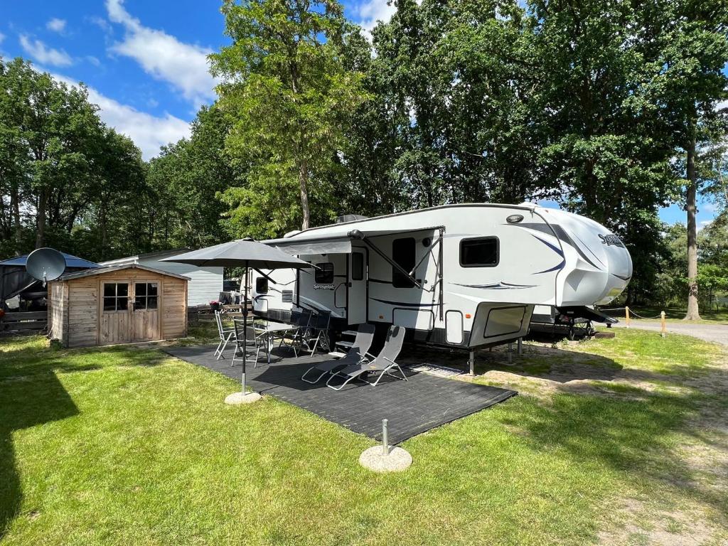 Ein weißer Wohnwagen parkt auf einem Feld neben Bäumen in der Unterkunft American Camping im US-Wohnwagen in Brandenburg an der Havel