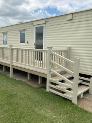 a mobile home with a porch and a deck at B&T caravans in Ingoldmells