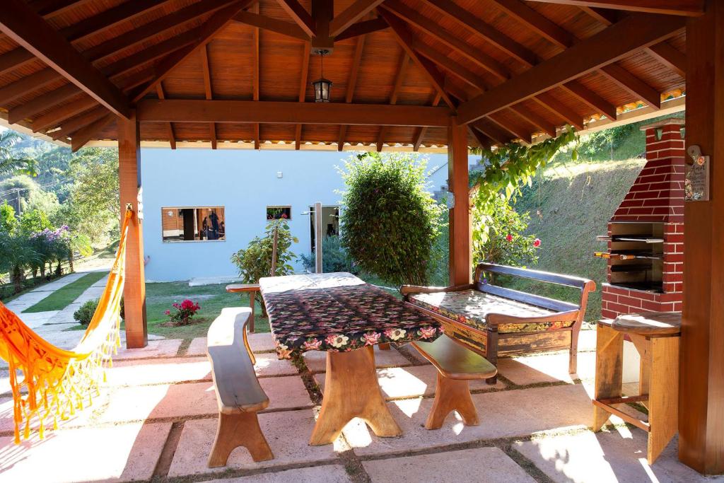 d'une terrasse avec une table, des chaises et un banc. dans l'établissement Casa de Campo com Churrasq em Marechal Floriano - ES, à Marechal Floriano