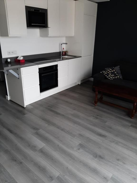 a kitchen with white cabinets and a table and a couch at Appartement cosy de centre ville in Charenton-le-Pont