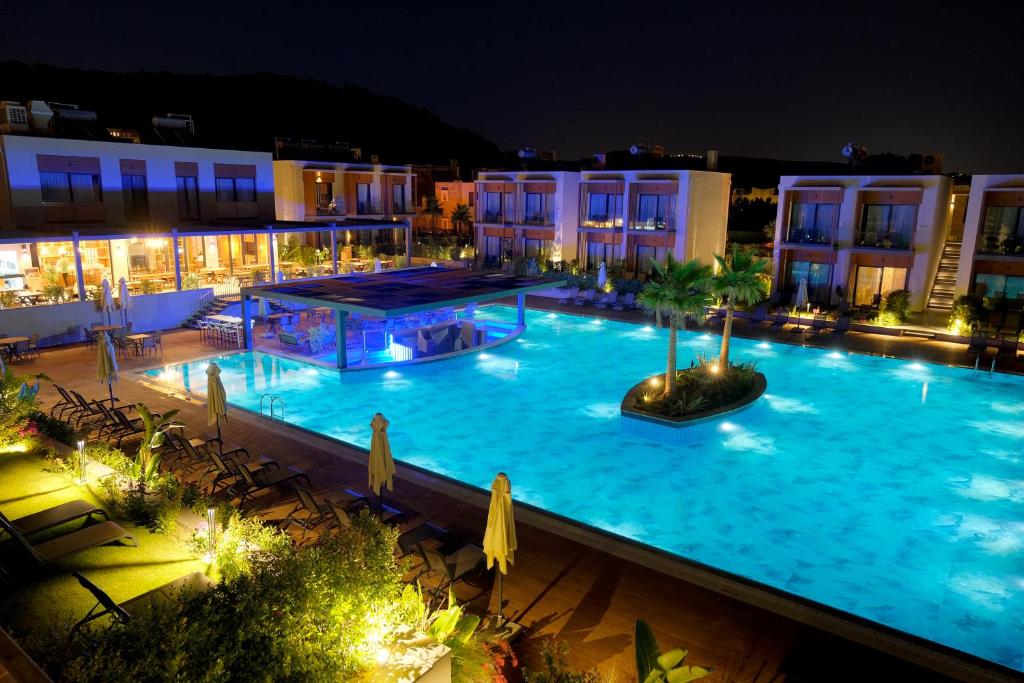 una gran piscina por la noche con edificios en Celeste Bella Luxury Hotel & Spa, en Ortakent
