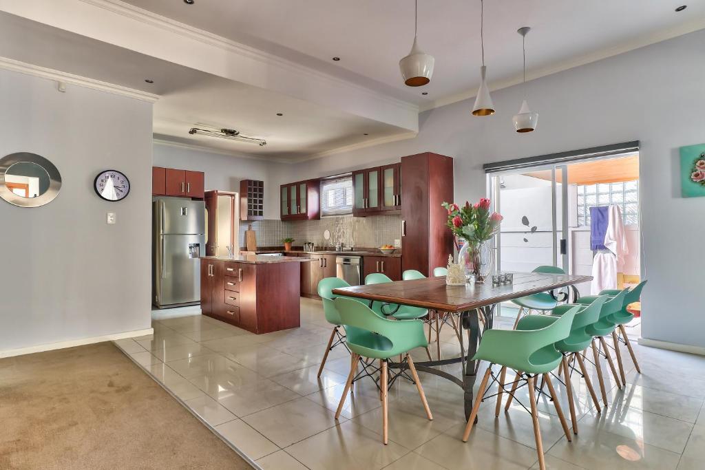 a kitchen with a wooden table and green chairs at SASHORES- 6 on Ellis in Cape Town