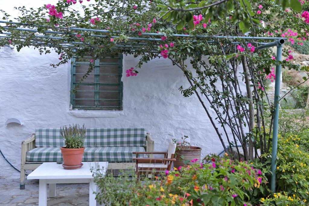 un patio con sofá, mesa y flores en Apatouria Farmhouse, en Ándros