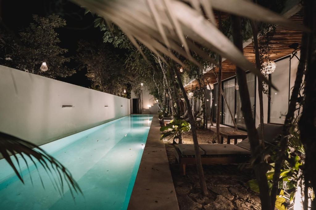 a swimming pool at night with trees around it at Unique & Stylish Apartment With Lovely Decked Terrace & Awesome Floating Pool In Tulum in Tulum