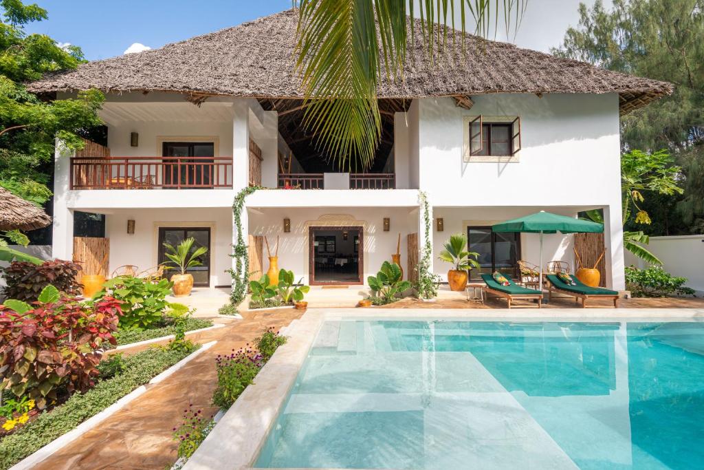 a villa with a swimming pool in front of a house at Daima Villas in Jambiani