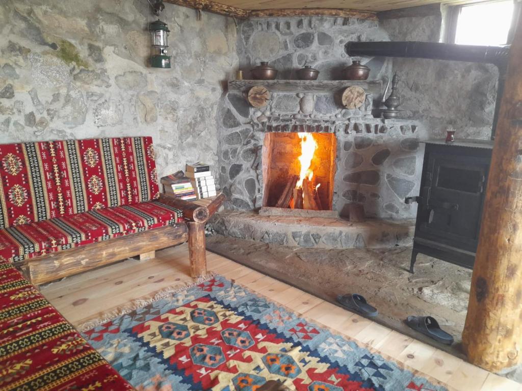 uma sala de estar com uma lareira de pedra e um sofá em Erdal Pansiyon em Çamlıhemşin