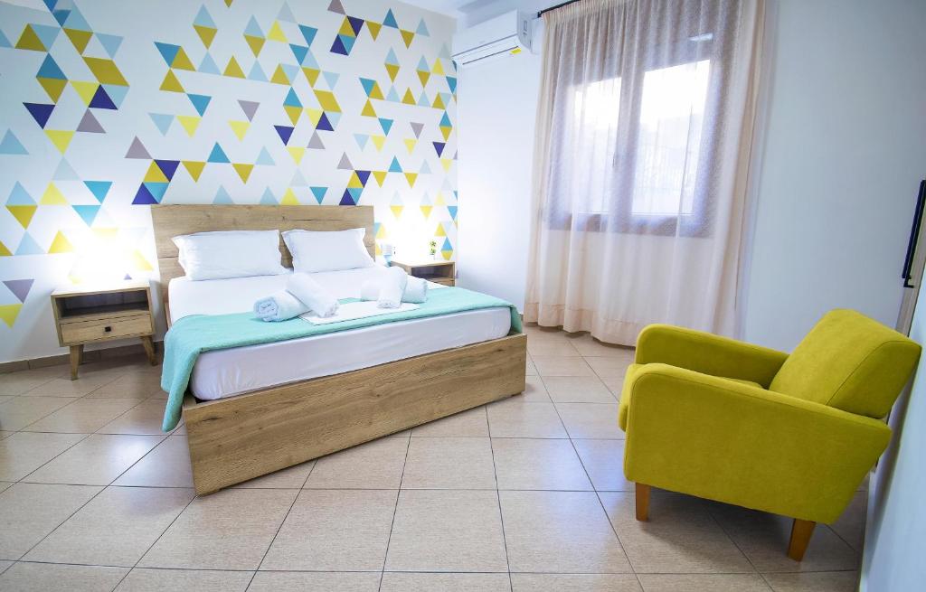 a bedroom with a bed and a yellow chair at Petite palace in Rethymno Town