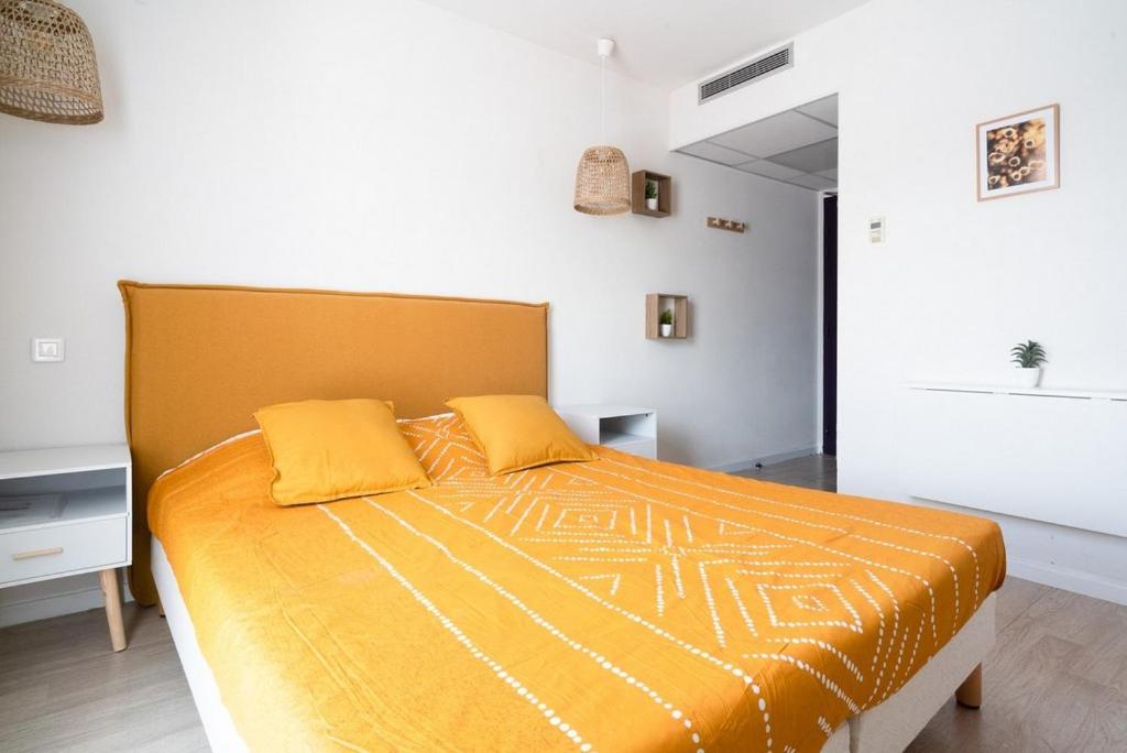 een slaapkamer met een groot bed met 2 gele kussens bij Joli studio proche gare et centre ville in Lourdes