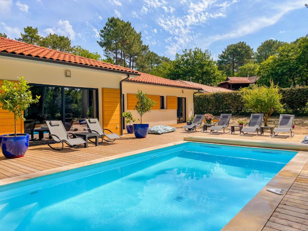 a swimming pool with chairs and a house at Magnifique villa avec piscine in Biscarrosse