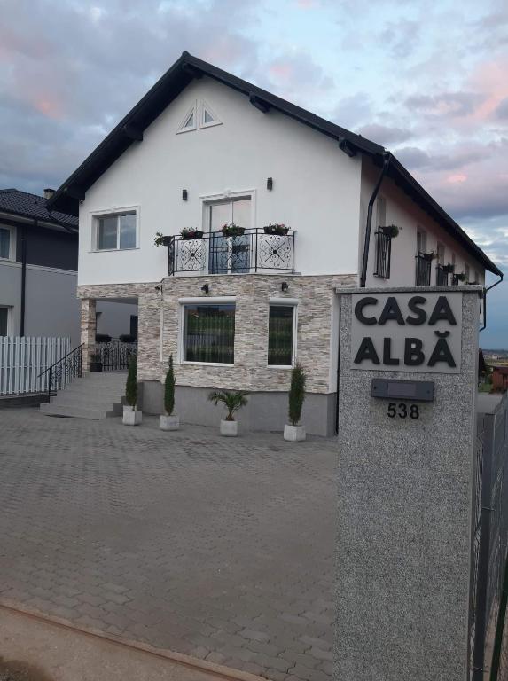 a white house with a sign in front of it at Casa Albă in Sănduleşti