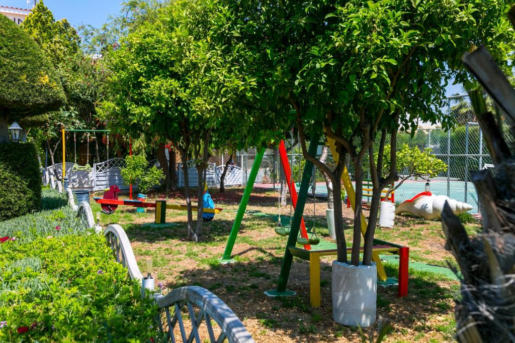 a park with a playground with trees and swings at Fitosinn Hotel in Paphos