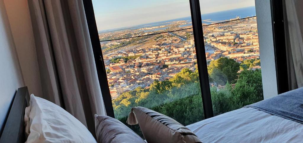 a bedroom with a view of a city from a window at Studio terrasse Indépendante Vue Exceptionnelle in Sète