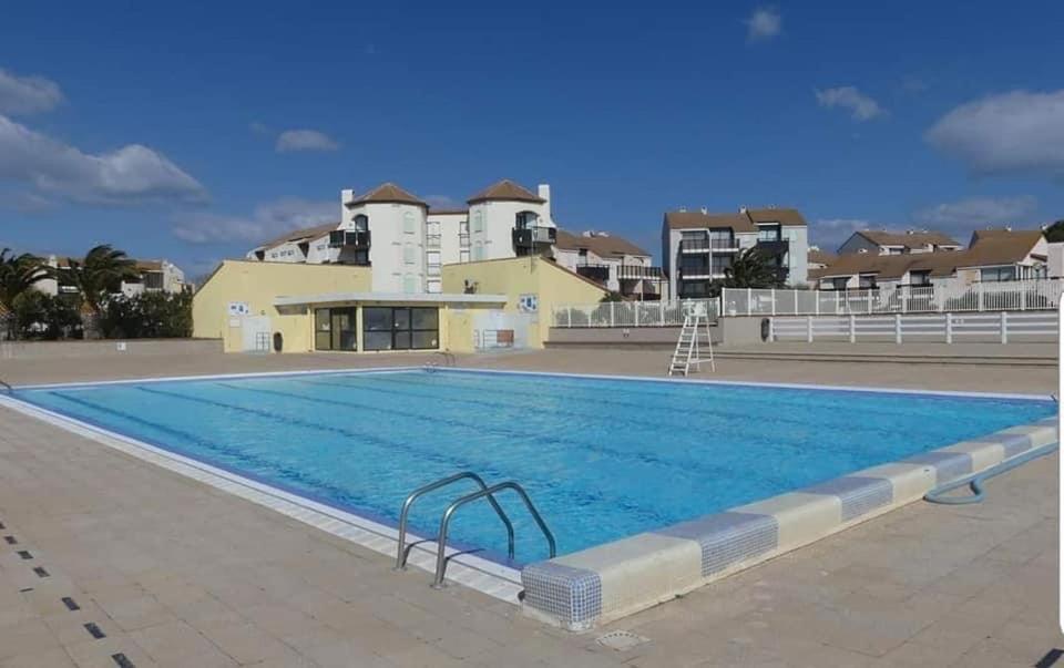 uma grande piscina com edifícios ao fundo em Superbe appartement avec piscine em Le Barcarès