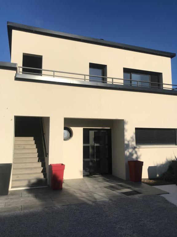 un edificio blanco con escalera y puerta en Aux Grès des Vagues, en Lion-sur-Mer