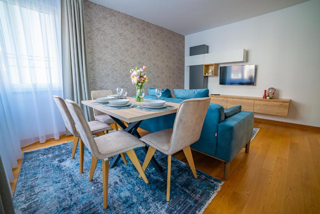 Kedar apartment في نوفي ساد: غرفة طعام مع طاولة وأريكة زرقاء