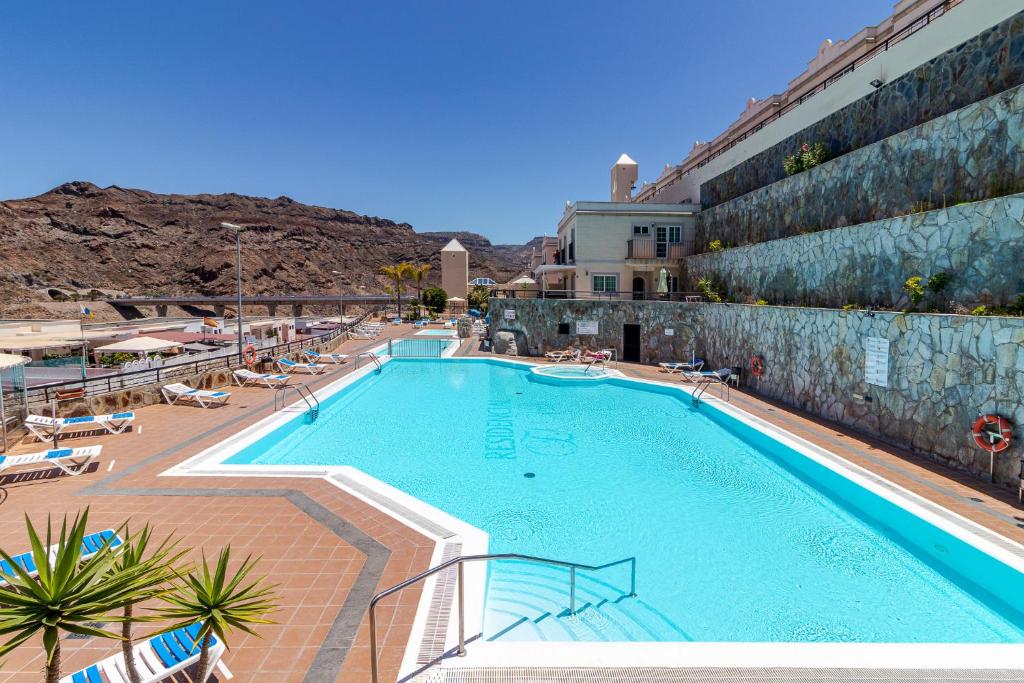 a large swimming pool next to a building at Apartamento en Puerto Rico in Mogán