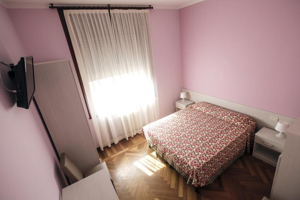 niewielka sypialnia z łóżkiem i oknem w obiekcie Italy Inn w Genui