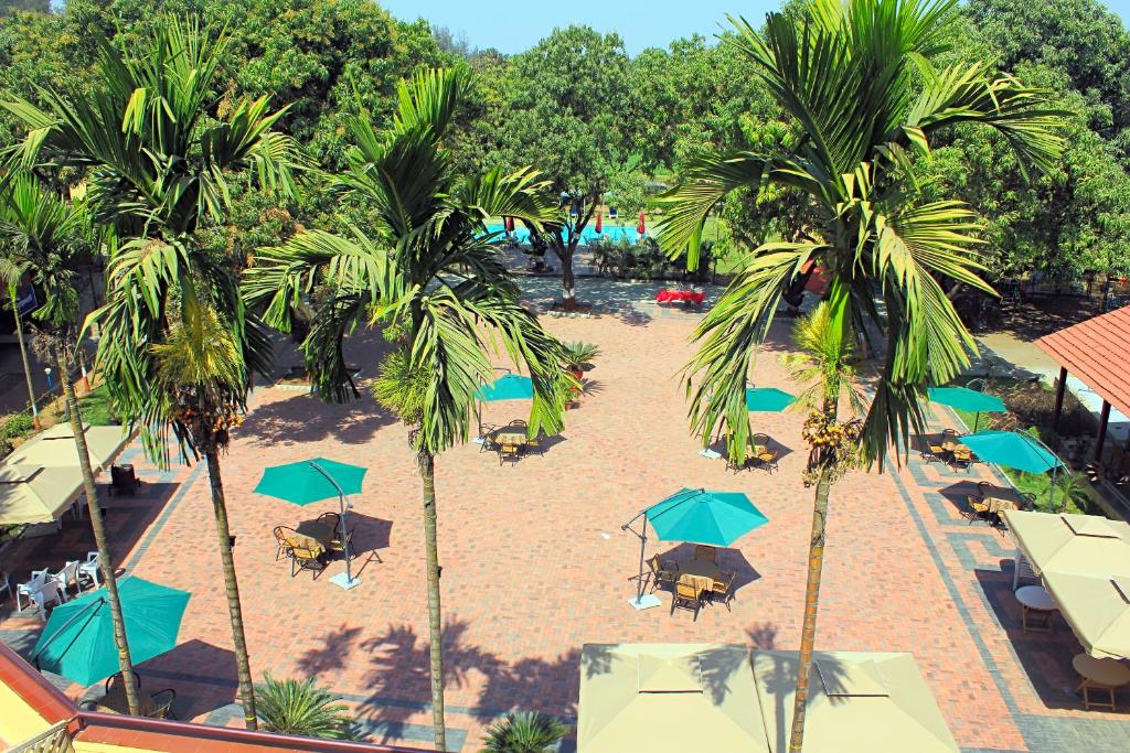 a beach with umbrellas and chairs and palm trees at Damanganga Valley Resort Silvassa in Silvassa