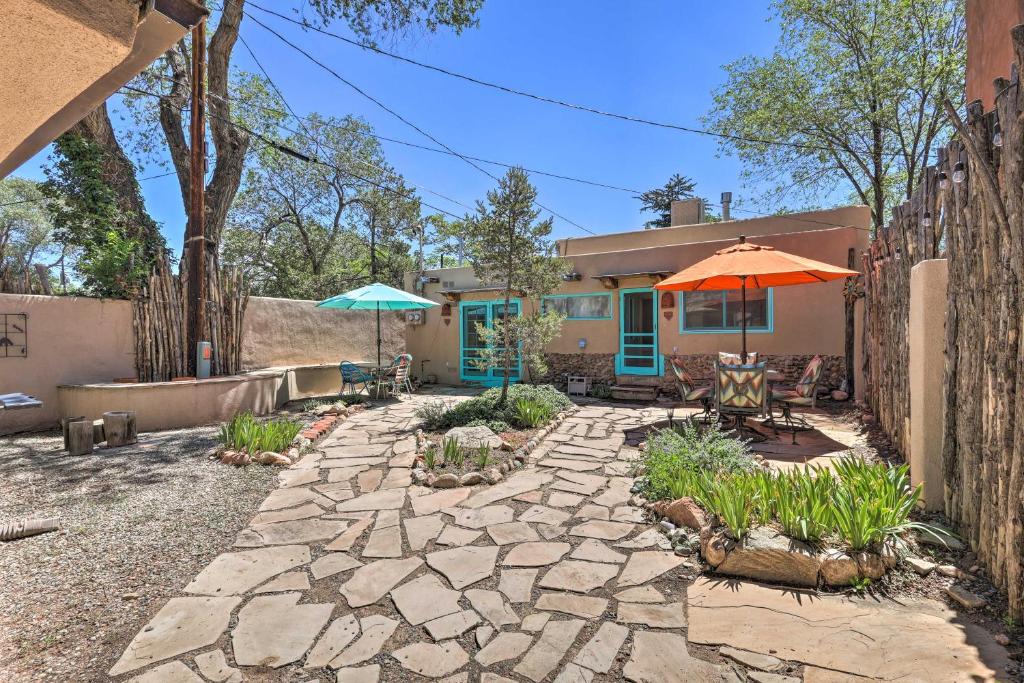 eine Terrasse mit Sonnenschirm und Stühlen und ein Haus in der Unterkunft Authentic Adobe Abode Less Than 1 Mile to Sante Fe Plaza! in Santa Fe
