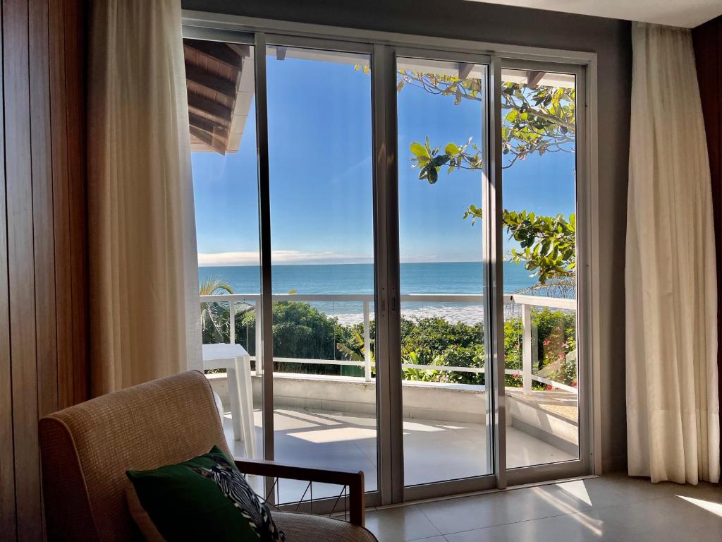 Habitación con una gran puerta corredera de cristal con vistas al océano. en Vivencie Esta Experiência Beira Mar, en Bombinhas