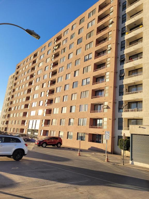 a large apartment building with cars parked in a parking lot at Atacama Valley 03 in Copiapó