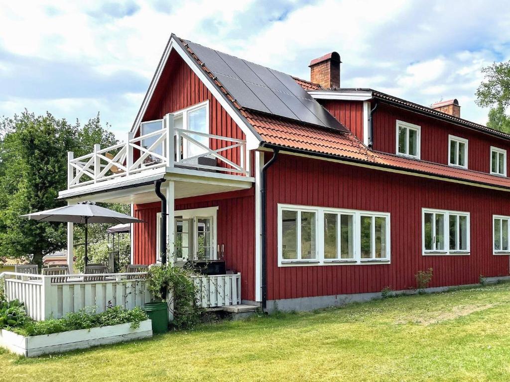 a red house with a red roof and a balcony at 6 person holiday home in VRETA KLOSTER in Vreta Kloster