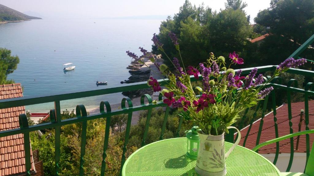 un jarrón de flores sobre una mesa con vistas al agua en Apartments Toni en Trogir