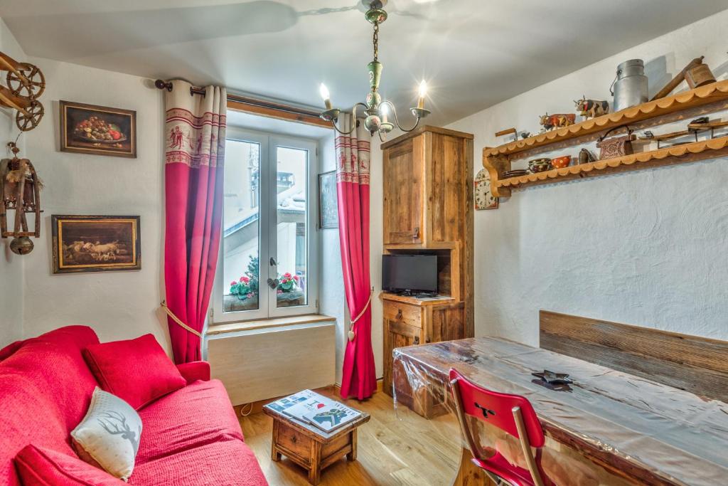 uma sala de estar com um sofá vermelho e uma mesa em Appartement de l'Alpage - Welkeys em Megève