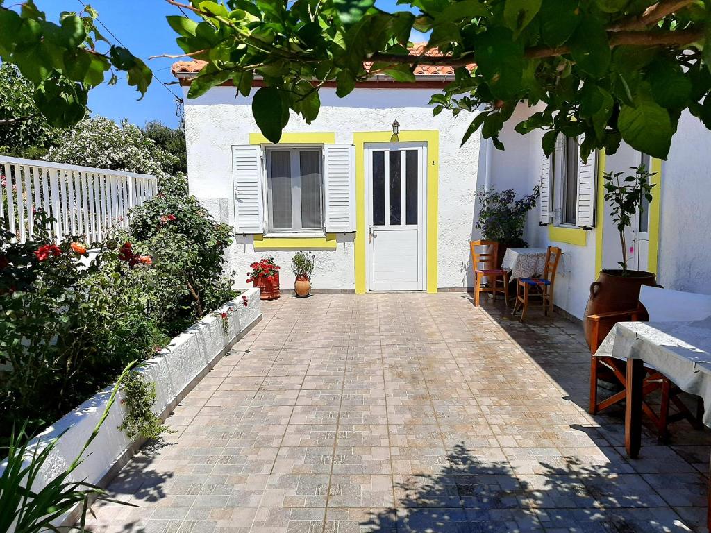 a white house with a yellow door and a patio at Lemon Garden 1 in Karídhion