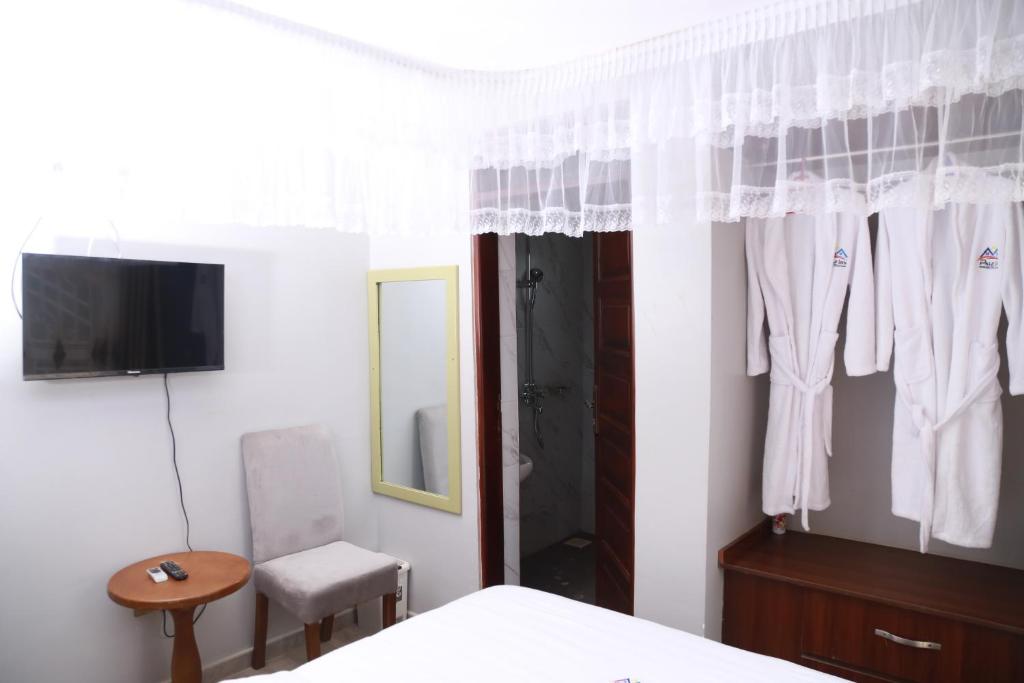 a bedroom with a bed and a tv and a mirror at Pals Inn in Busia
