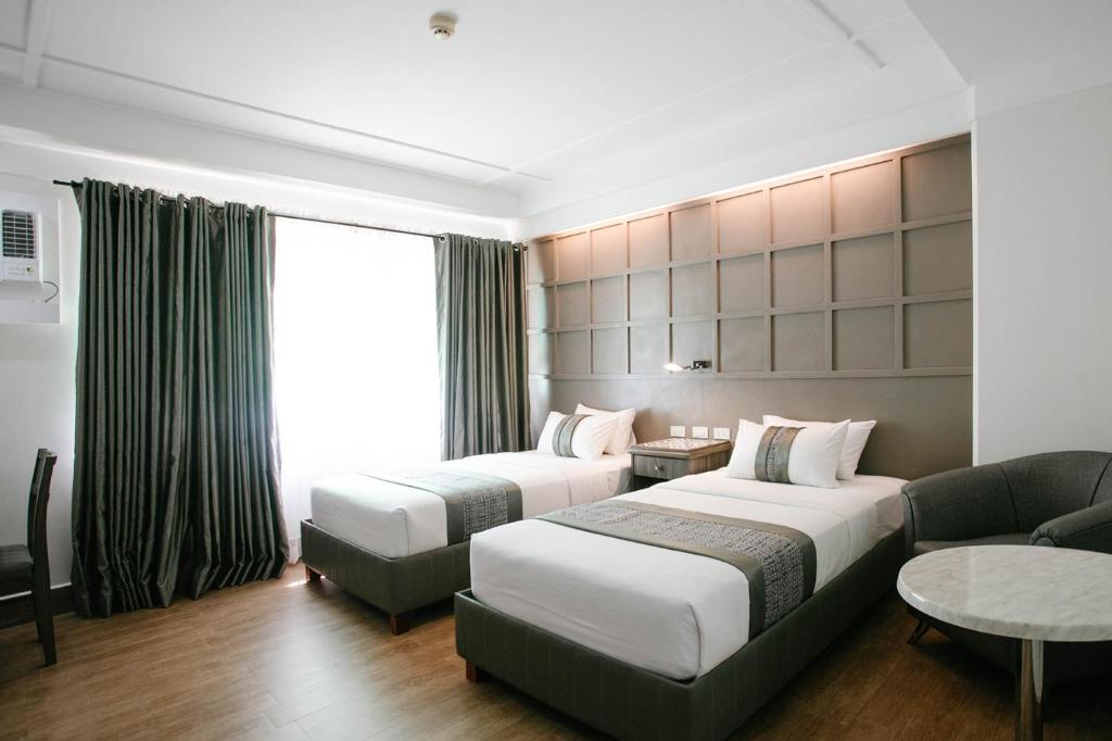 Diamond Suites and Residences في مدينة سيبو: غرفة فندقية بسريرين واريكة