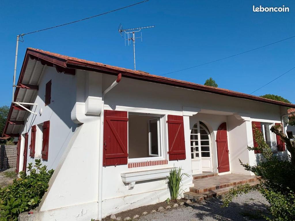 Une petite maison blanche avec volets rouges dans l'établissement Authentique Villa Landaise SOUSTONS 7pers., à Soustons