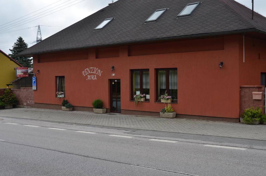 ein rotes Gebäude am Straßenrand in der Unterkunft Penzion Aura in Dvůr Králové nad Labem