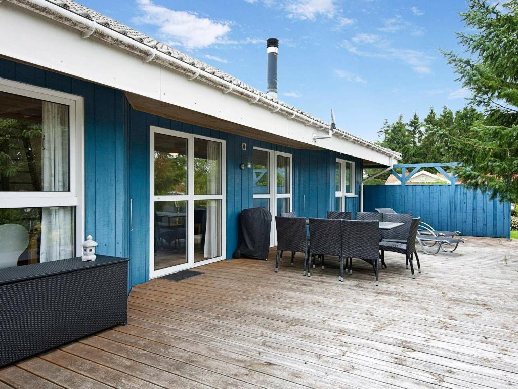 a blue house with a deck with a table and chairs at 8 person holiday home in Hejls in Hejls