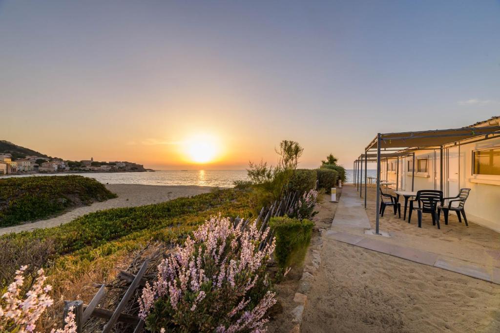 una casa en la playa con la puesta de sol en el fondo en L'Escale Plage, en Algajola