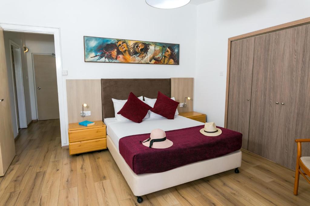 a bedroom with a large bed with red pillows at Fitosinn Hotel in Paphos