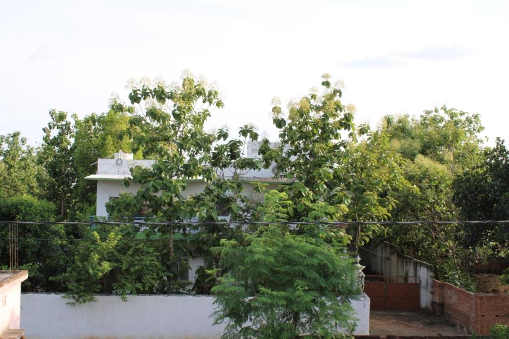 una casa bianca con degli alberi di fronte di "Priyadarshi Villa" Free pickup in ac car from Jasidih Railway station or Deoghar Airport a Deoghar