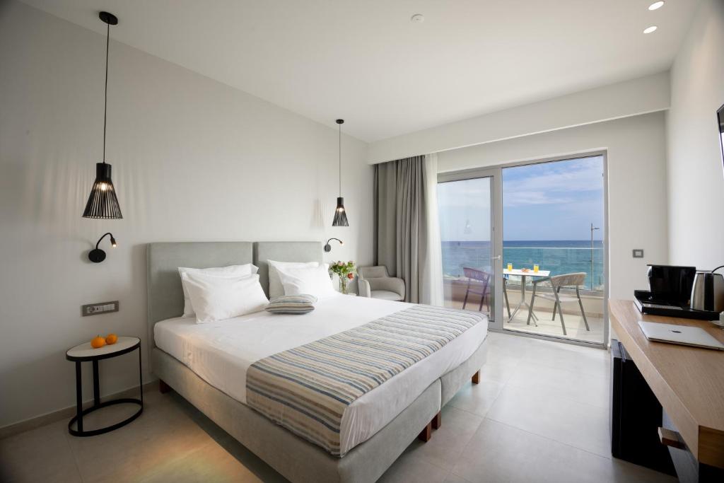 a bedroom with a bed and a view of the ocean at Batis Beach Hotel in Rethymno Town